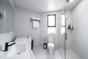 A modern bathroom with a white sink, toilet, and shower. - Tyms Elegant 4BR 2BA Apt Xujiahui Malls (Shanghai)