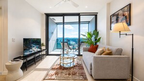 Ein modernes Wohnzimmer mit Flachbildfernseher, einer Couch, einem Couchtisch und einem Balkon mit Blick.
