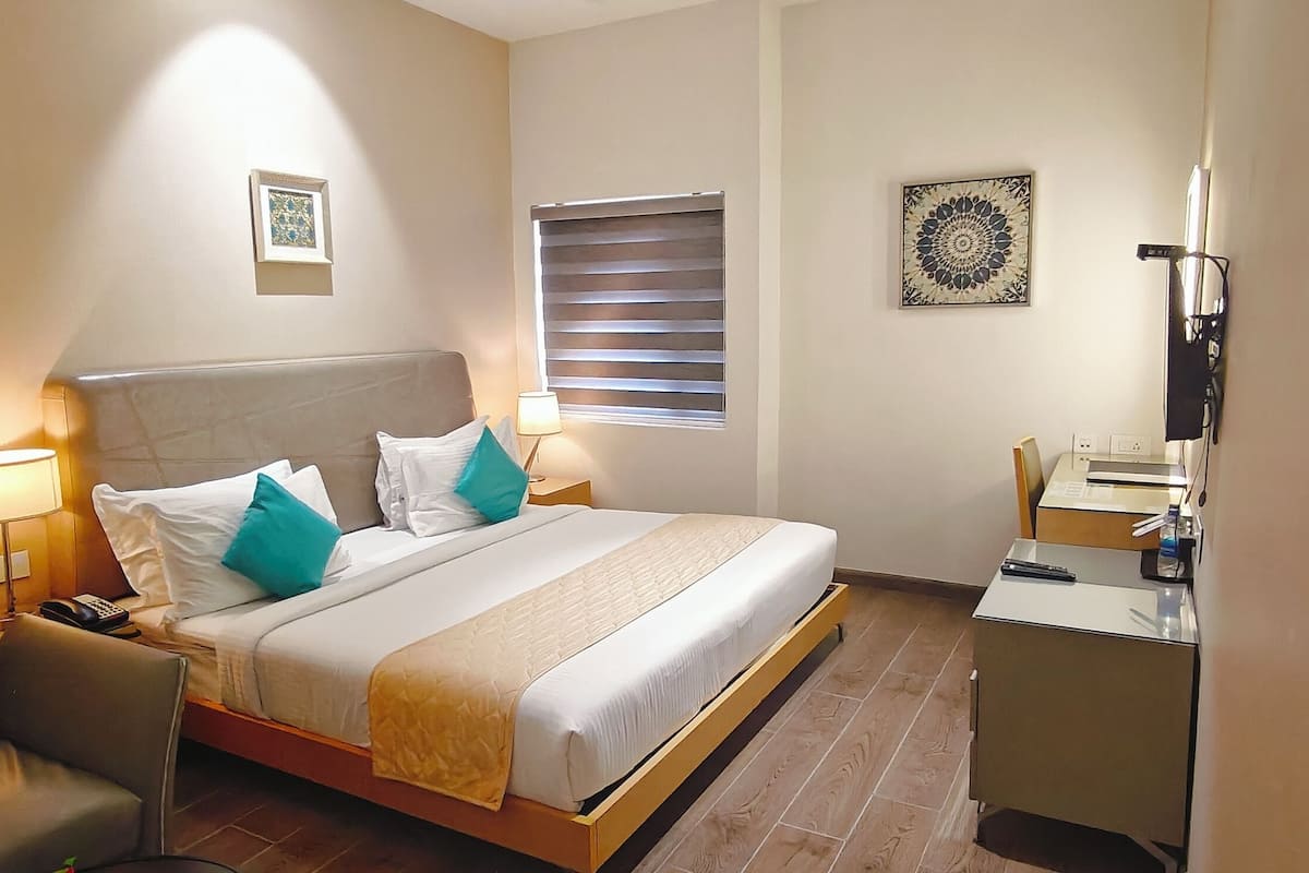 Ein Hotelzimmer mit einem Bett, Nachttischlampen, einem Schreibtisch und einem Stuhl.