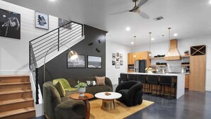 Una sala moderna con una escalera, una zona de cocina y un comedor.