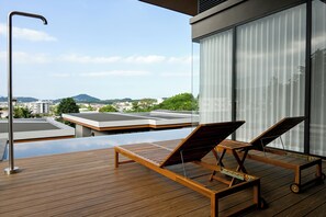 A wooden deck with two sun loungers and a modern building with large windows. -  Wora Phuket (Ratsada)
