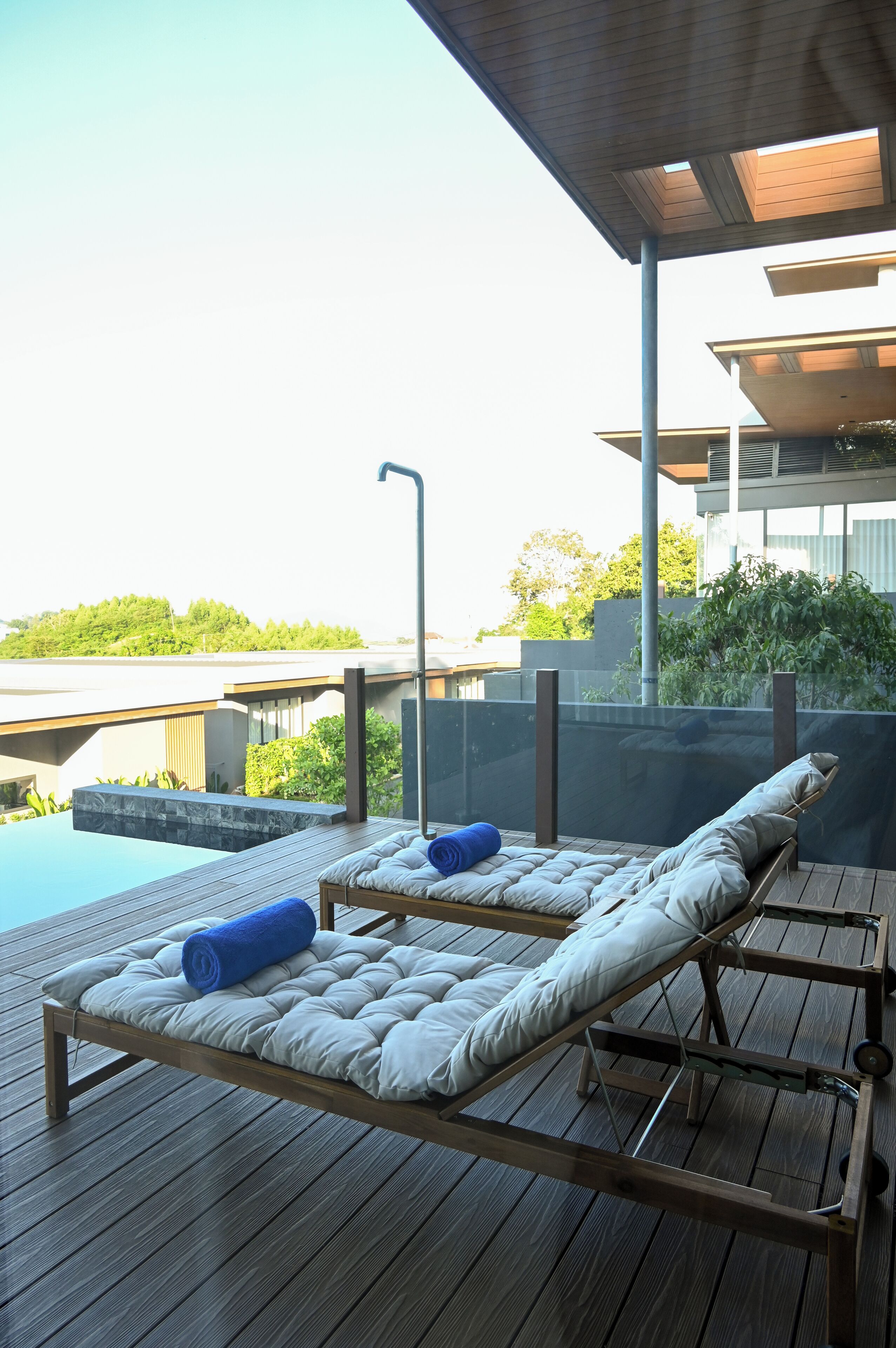 Una terraza de madera con dos sillas de descanso, una con una toalla azul.