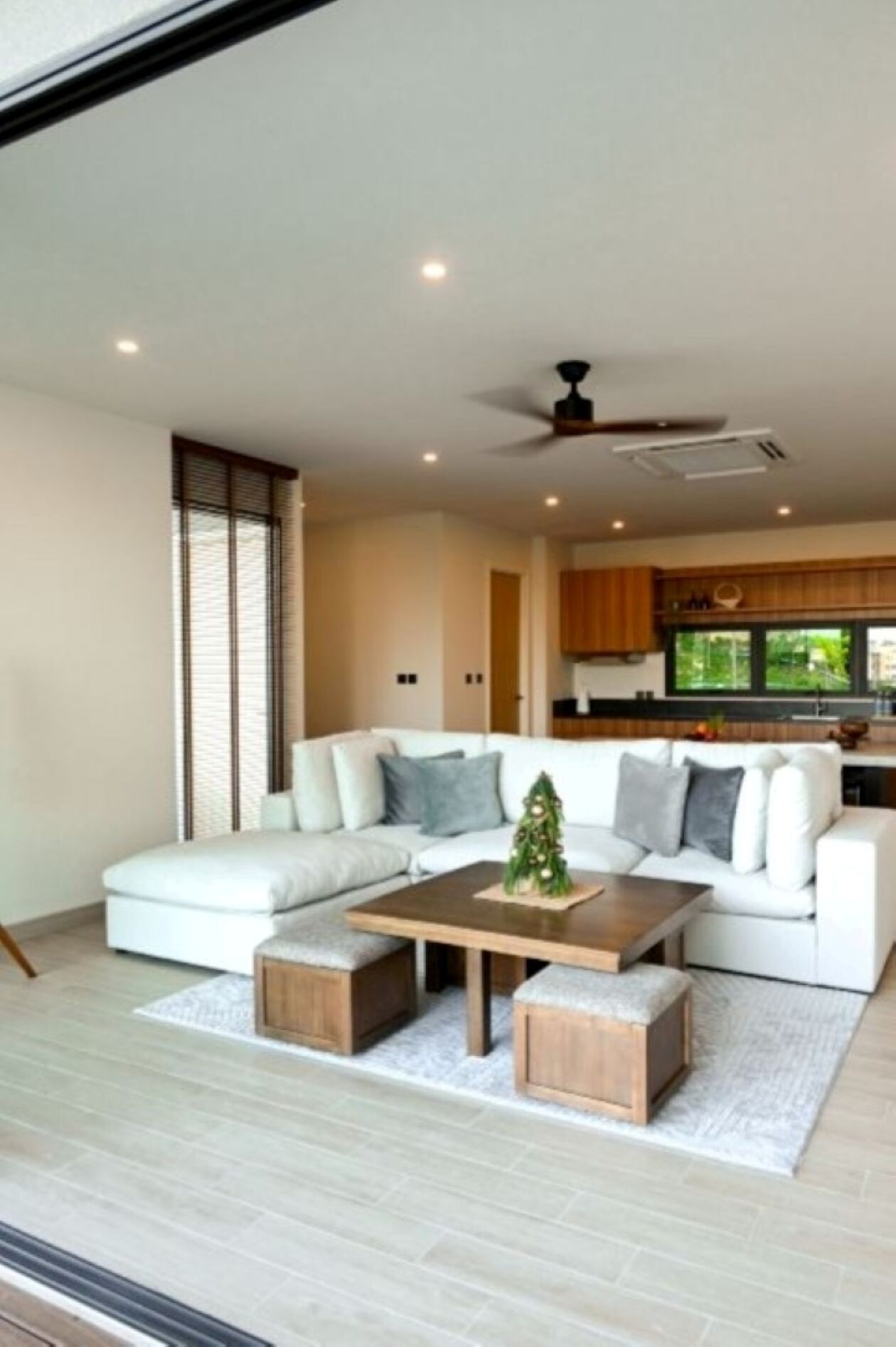 A modern living room with a sectional sofa, a coffee table, and a small Christmas tree.