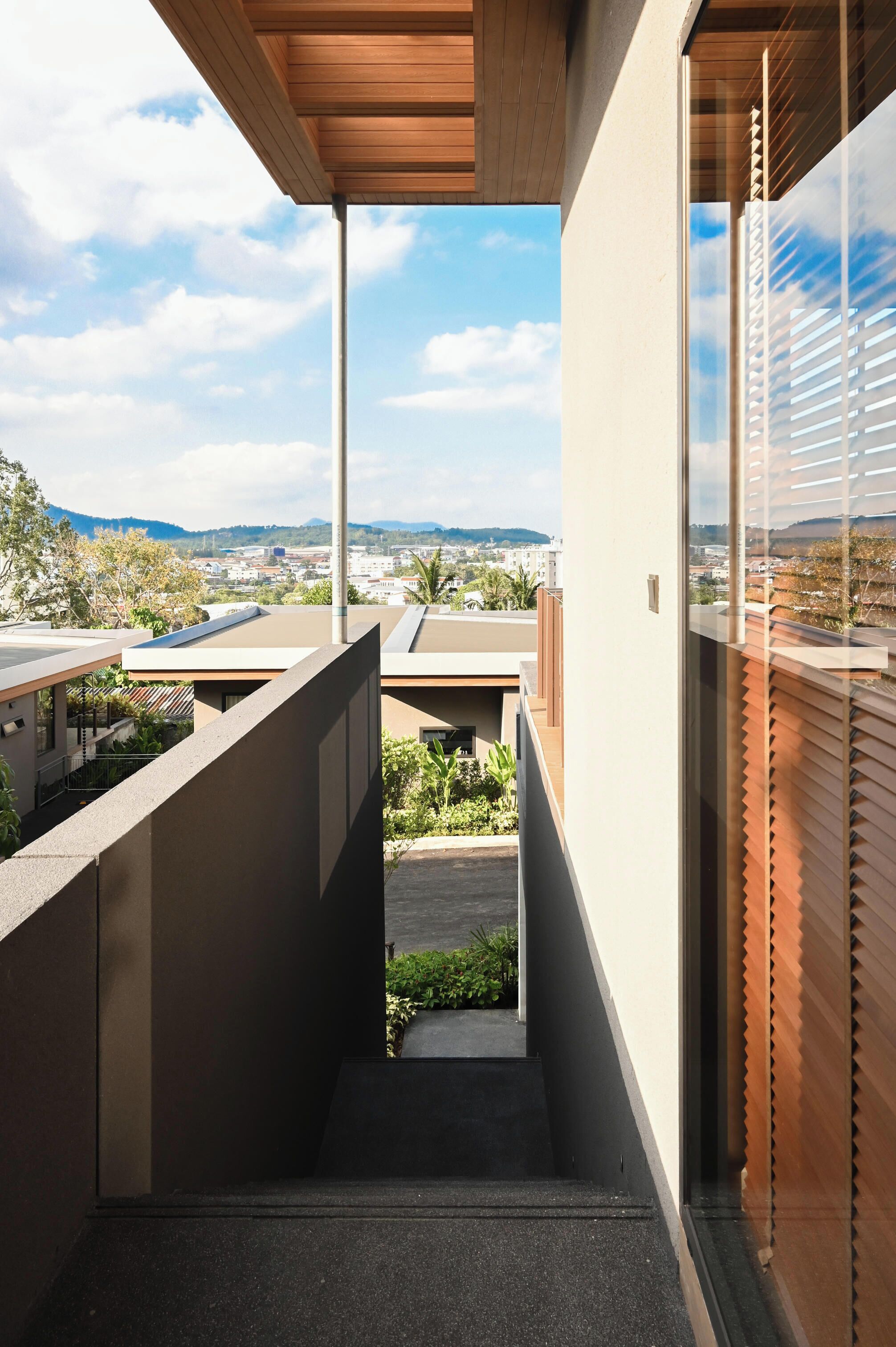 Un balcón moderno al aire libre con vistas a un paisaje urbano y colinas.