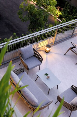 A rooftop terrace with wicker furniture, a small table, and a lantern. -  Wora Phuket (Ratsada)