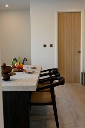 A dining area with a table, chairs, and a door in the background. -  Wora Phuket (Ratsada)
