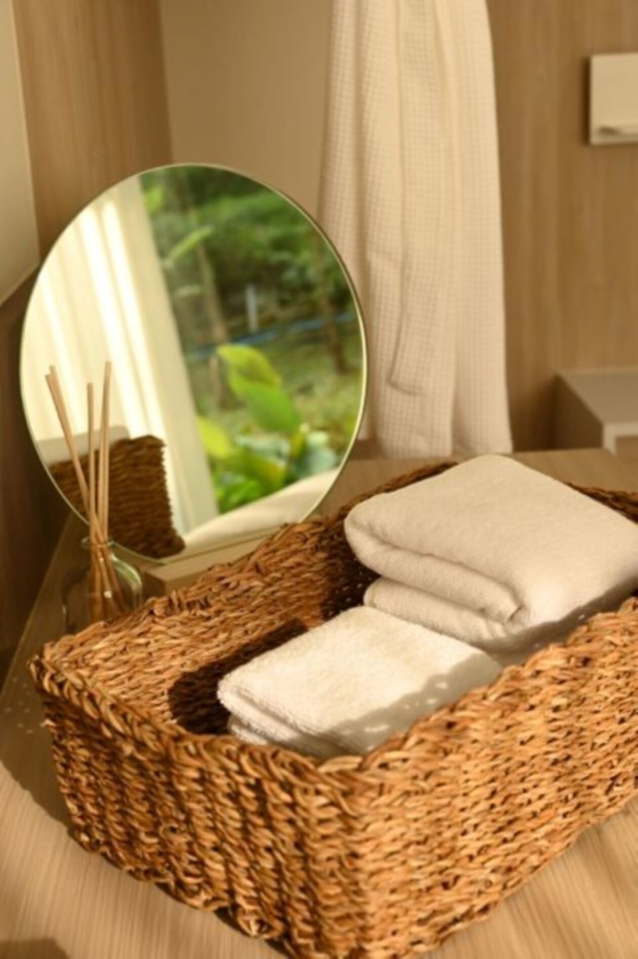A wicker basket with folded towels on a wooden surface.