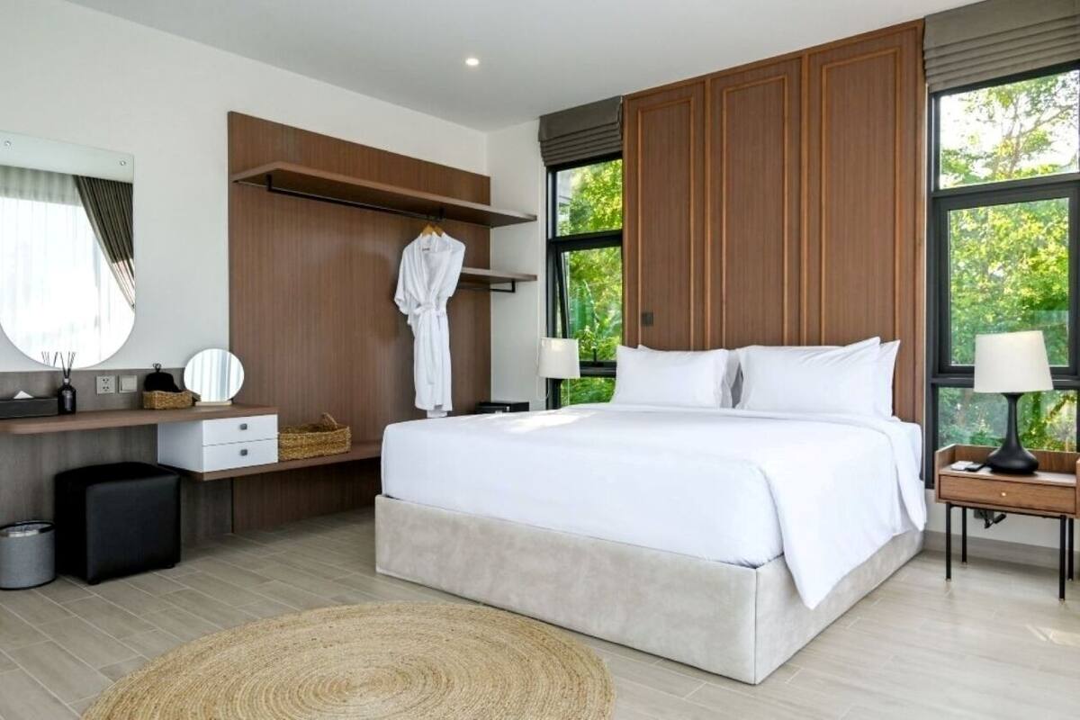 Un dormitorio moderno con una cama grande, paneles de madera, un tocador con espejo y vistas a zonas verdes.