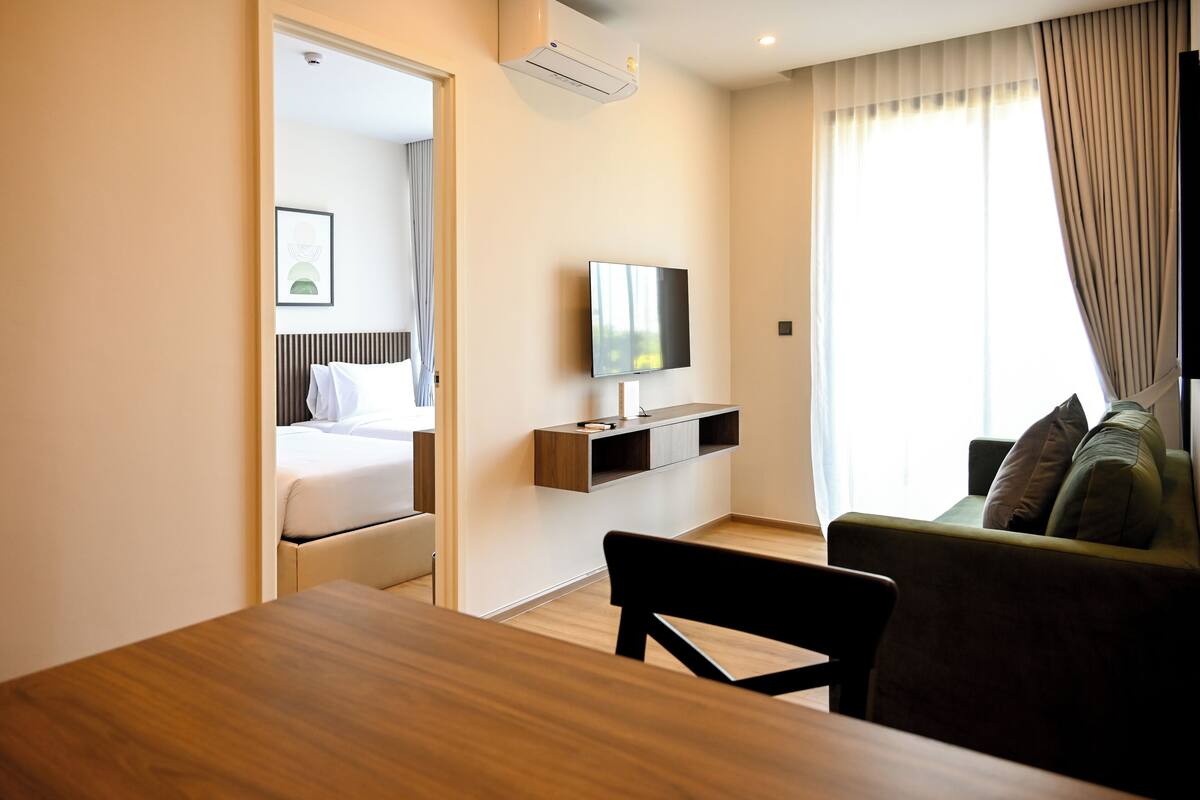 Una habitación de hotel con cama, televisor, sofá y mesa de comedor.