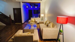 A modern living room with a wooden floor, a sofa set, a coffee table, and a red floor lamp. - Luxury 3BHK Villa Stay Royal in Aerocity Mohali (Mohali)