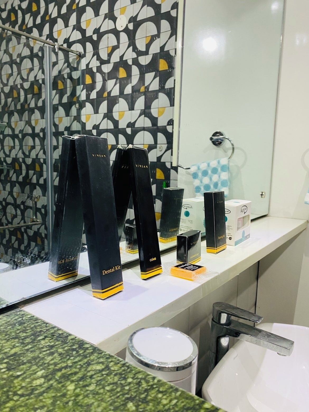 A bathroom with a mirror, a sink, and a countertop displaying dental kits and other toiletries.