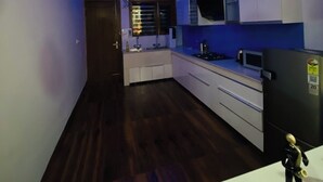 A modern kitchen with dark wood flooring, white cabinets, and blue LED lighting on the ceiling. - Luxury 3BHK Villa Stay Royal in Aerocity Mohali (Mohali)