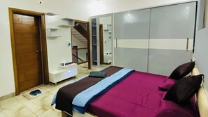 A modern bedroom with a bed, a wardrobe, a mirror, and a ceiling fan. - Luxury 3BHK Villa Stay Royal in Aerocity Mohali (Mohali)