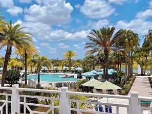 A pool area with lounge chairs and umbrellas, surrounded by palm trees.