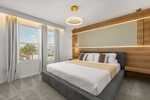 Ein modernes Schlafzimmer mit einem großen Bett, einem Holzkopfende und Blick ins Freie durch große Fenster.