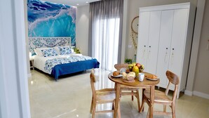 A bedroom with a large bed, a dining table with chairs, and a wardrobe.