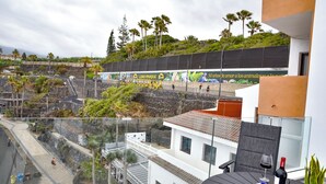 A balcony with a view of a park, a street, and a building with a mural.
