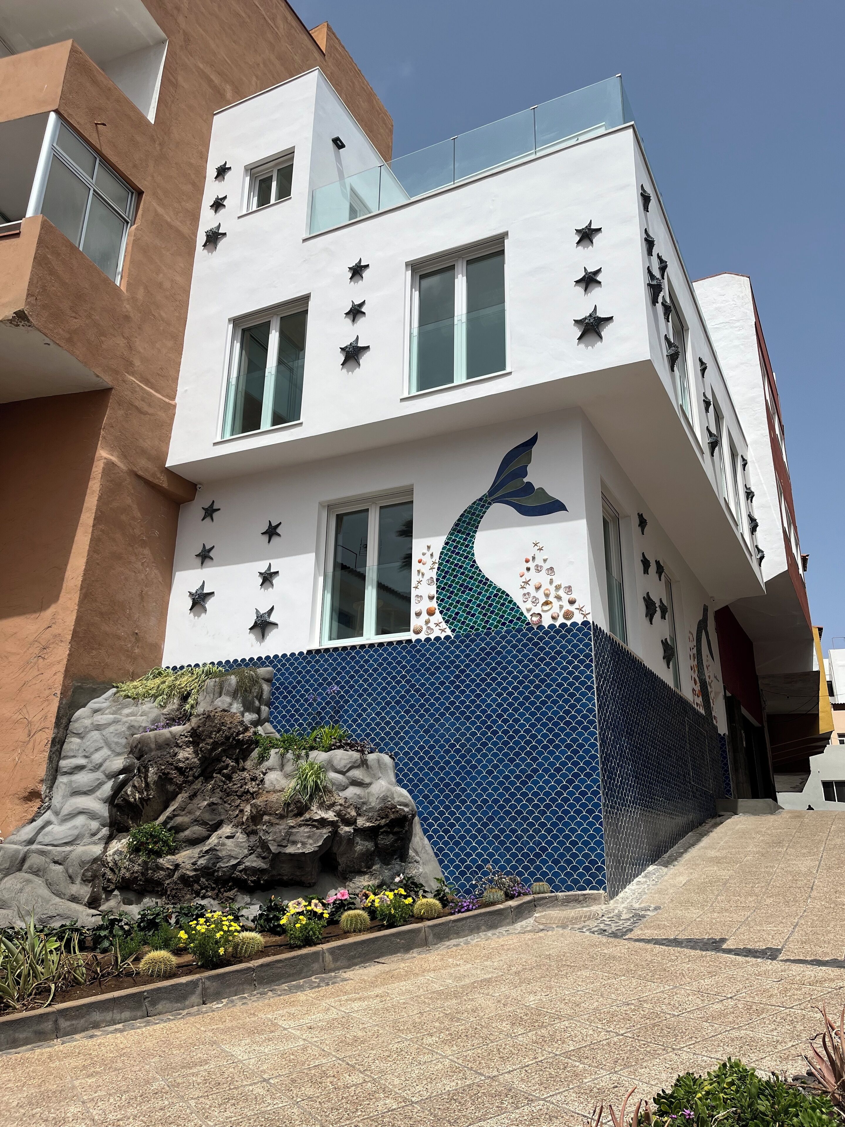Un bâtiment moderne à la façade blanche, doté de nombreuses fenêtres et orné de motifs décoratifs en forme d’étoiles.