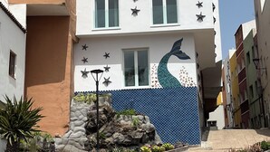 A multi-story building with a white facade, star-shaped decorations, and a blue tiled section with a dolphin mural.