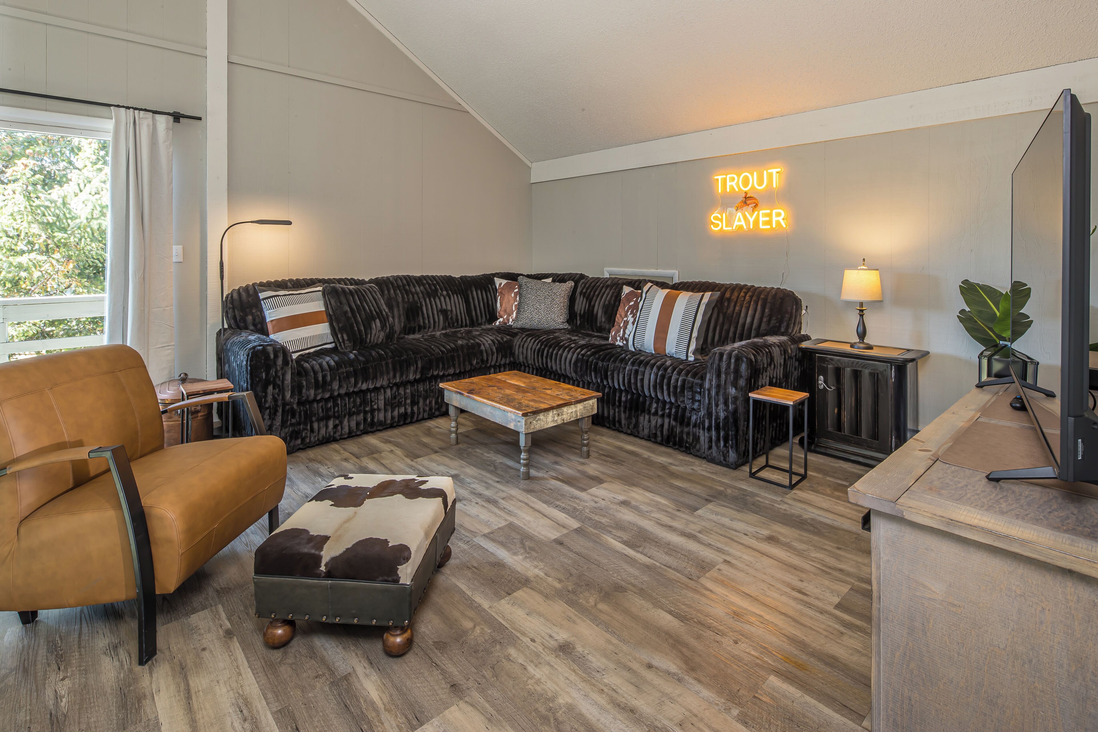 A modern living room with a sectional sofa, a leather armchair, a wooden coffee table, and a small side table with a lamp.