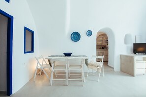 A modern, minimalist living space with a dining area, kitchen, and seating area. - Blu Bianco cave loft (Oia)