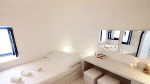 A small, clean room with a bed, a bedside table, and a mirror.