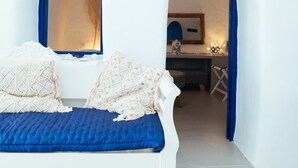 A white bed with blue bedding in a room with white walls and blue archways.