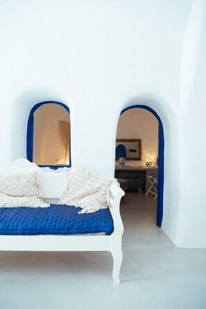 A white bed with blue bedding in a room with white walls and blue archways. - Blu Bianco cave loft (Oia)