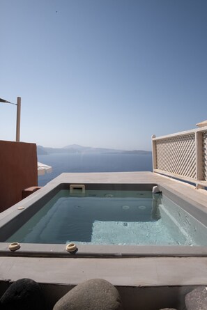 A hot tub with a clear view of the sea and distant mountains.