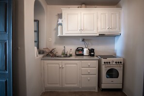 A compact kitchen with white cabinets, a built-in oven, and a coffee maker.