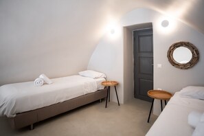 A bedroom with a bed, a small table, a mirror, and a door.