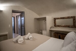 A hotel room with a bed, a bathroom with a mirror, and a hallway leading to other rooms.