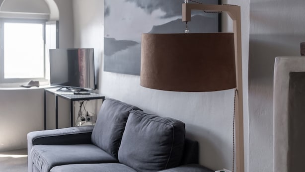 A modern living room with a grey sofa, a small table, a lamp, and a painting on the wall.