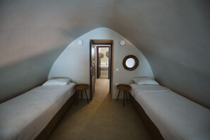 Een slaapkamer met twee eenpersoonsbedden, een klein tafeltje en een deur naar een andere kamer.