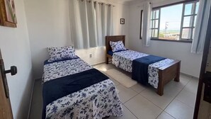 A room with two beds, a window with curtains, and a ceiling fan. - Blue Wave Hostel (Serra)