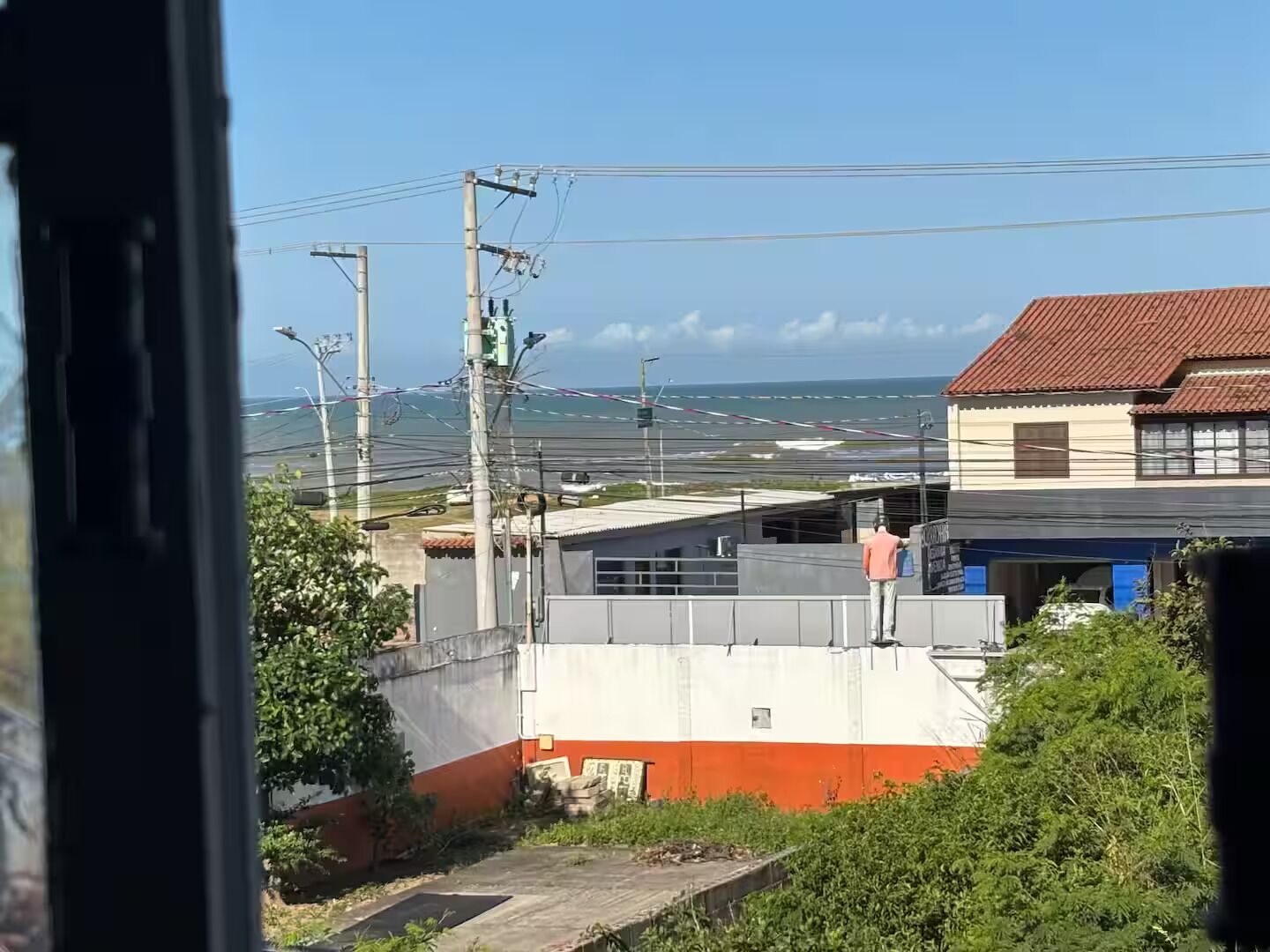 Vista de uma área costeira com um edifício de telhado vermelho e parede branca.