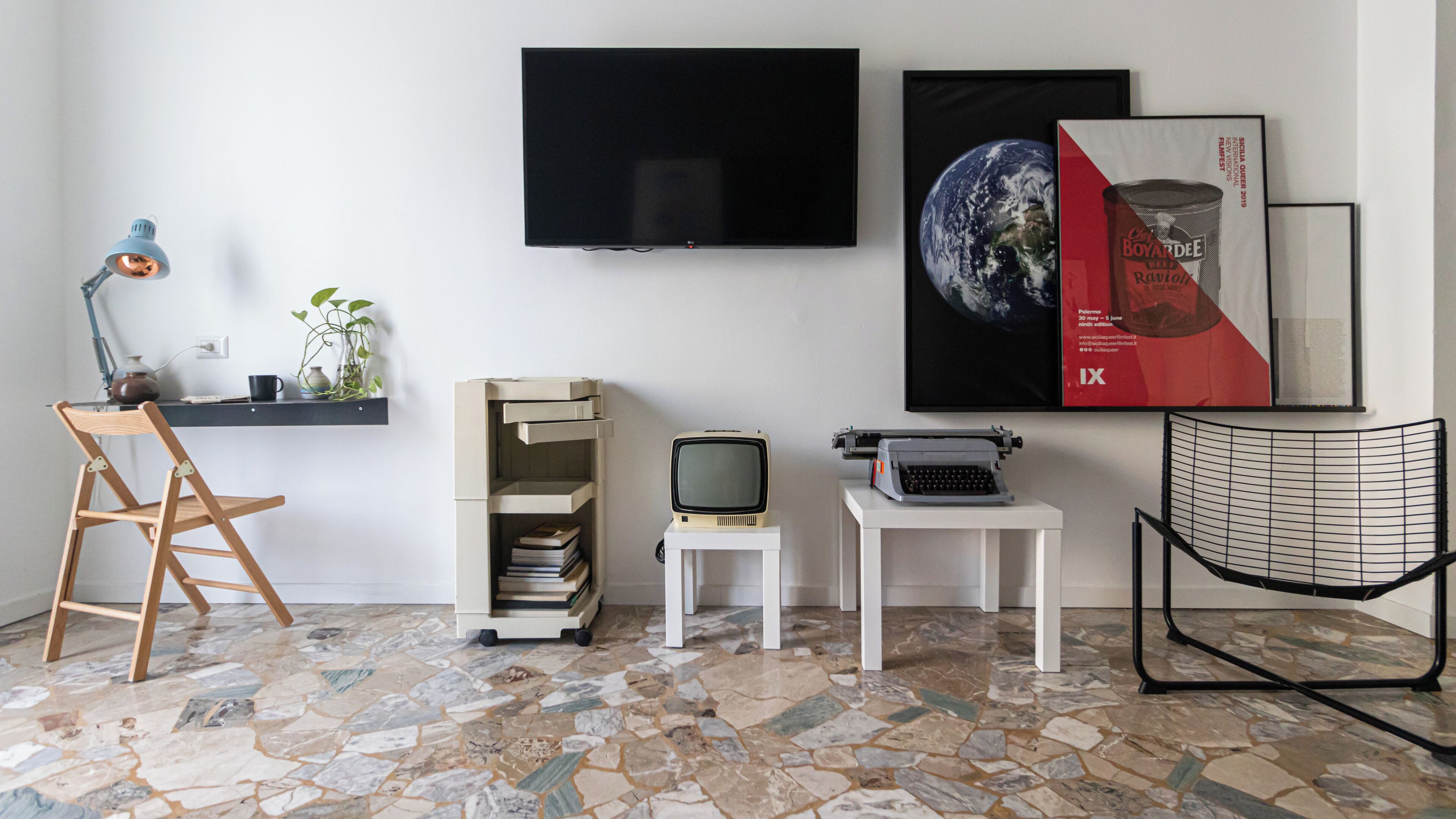 Ein modernes Wohnzimmer mit Flachbildfernseher, einem alten Fernseher, einer Schreibmaschine und einem Sessel.