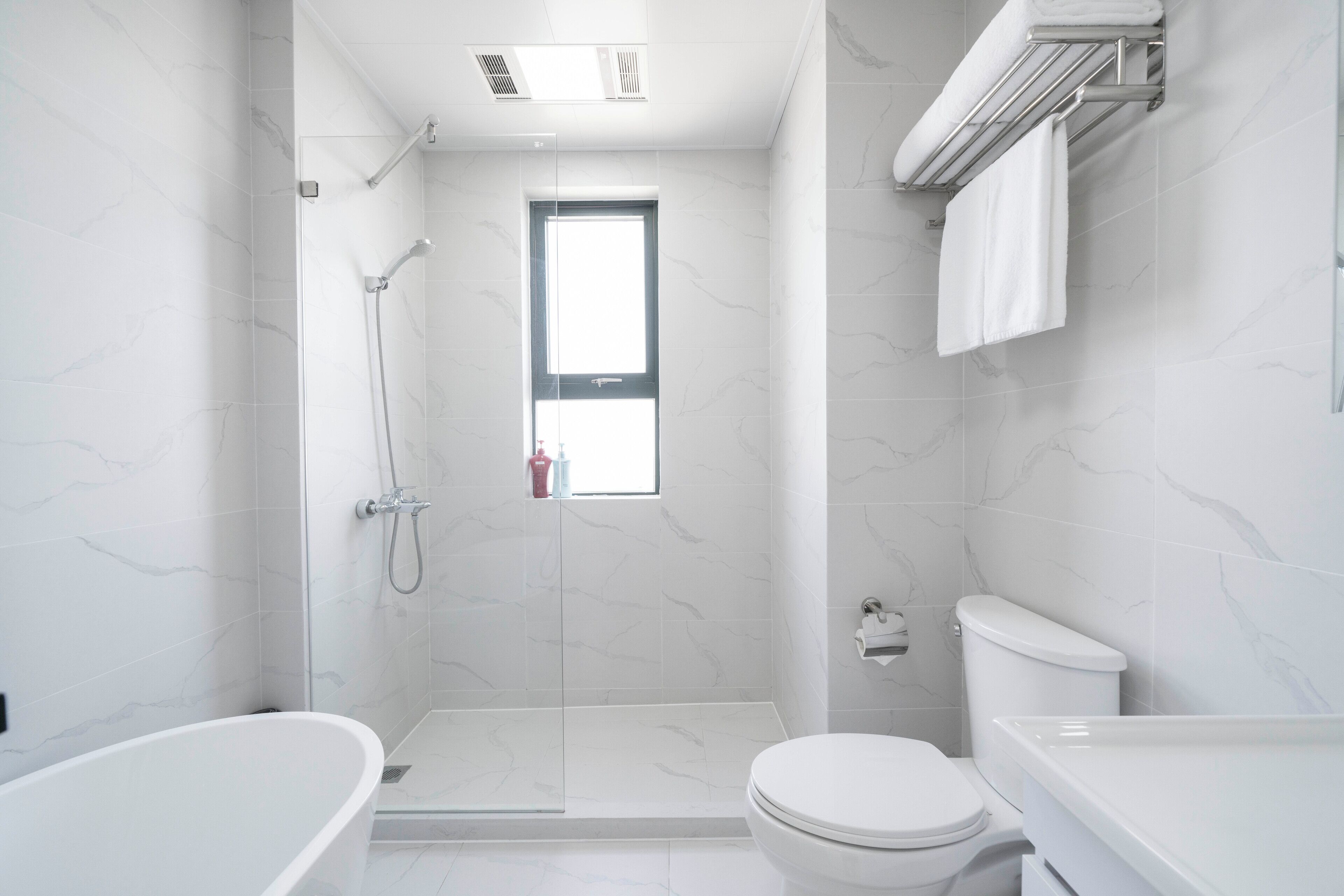 A modern bathroom with a glass-enclosed shower, a toilet, and a bathtub.