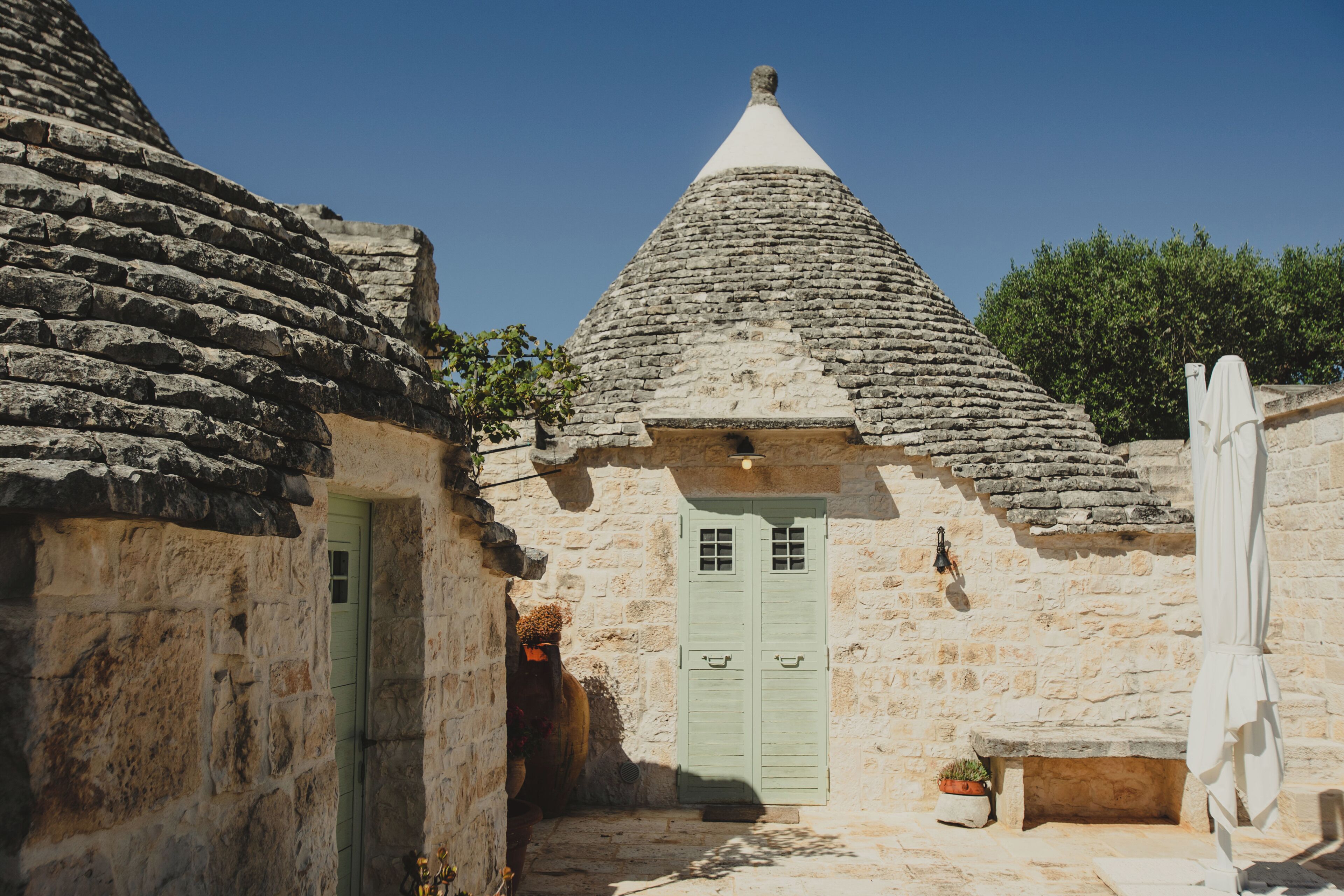 A stone building with a conical roof, a green door, and a bench.