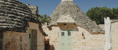 A stone building with a conical roof, a green door, and a bench.