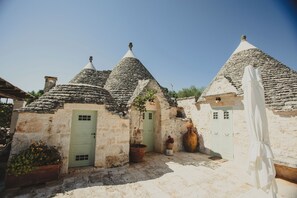 A traditional stone building with conical roofs, a green door, and a white cloth draped over a structure.