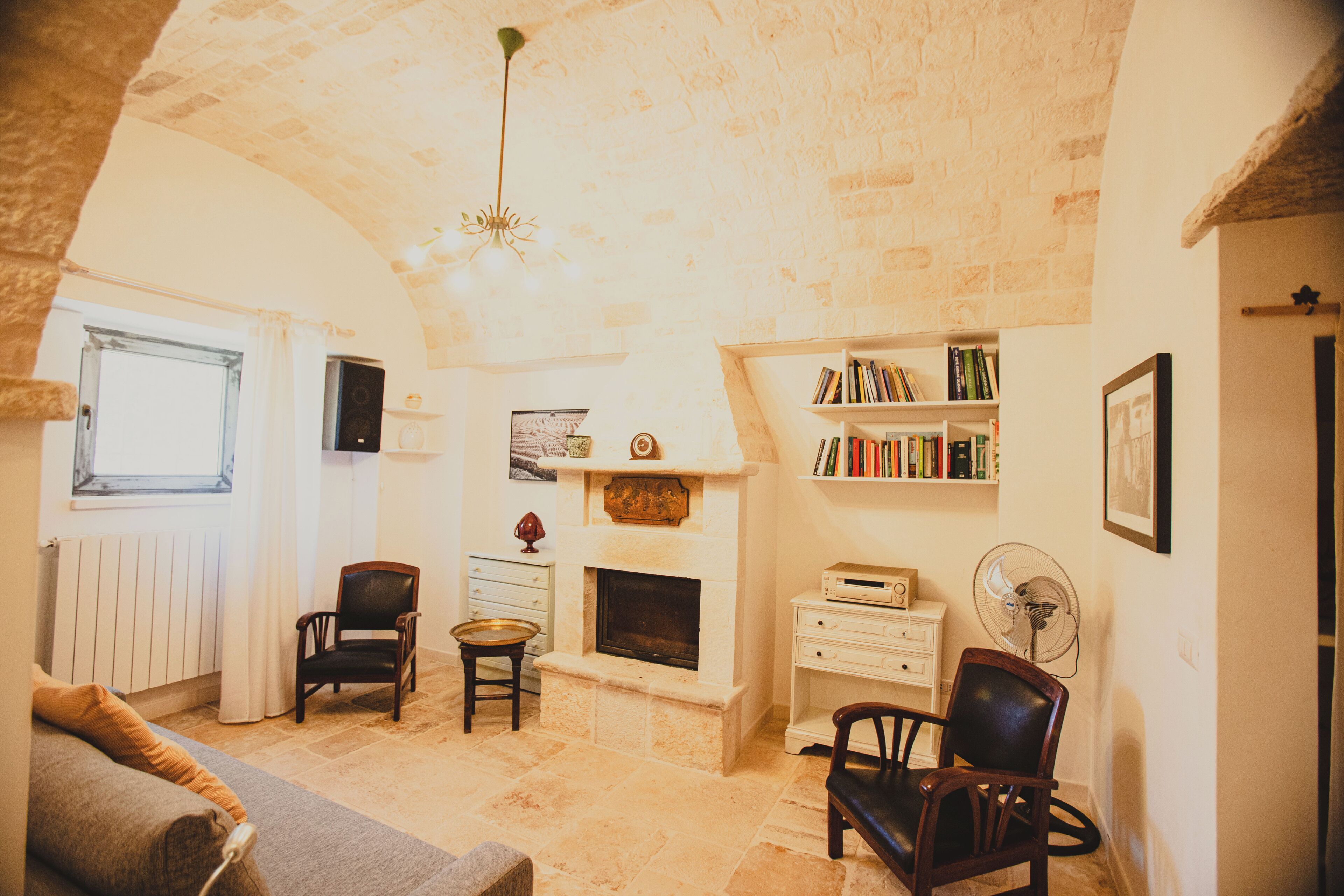A cozy living room with a fireplace, bookshelves, a sofa, and a dining table.