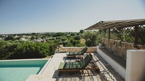 Une piscine sur le toit, dotée de chaises longues, un mur en pierre et une vue sur la ville.