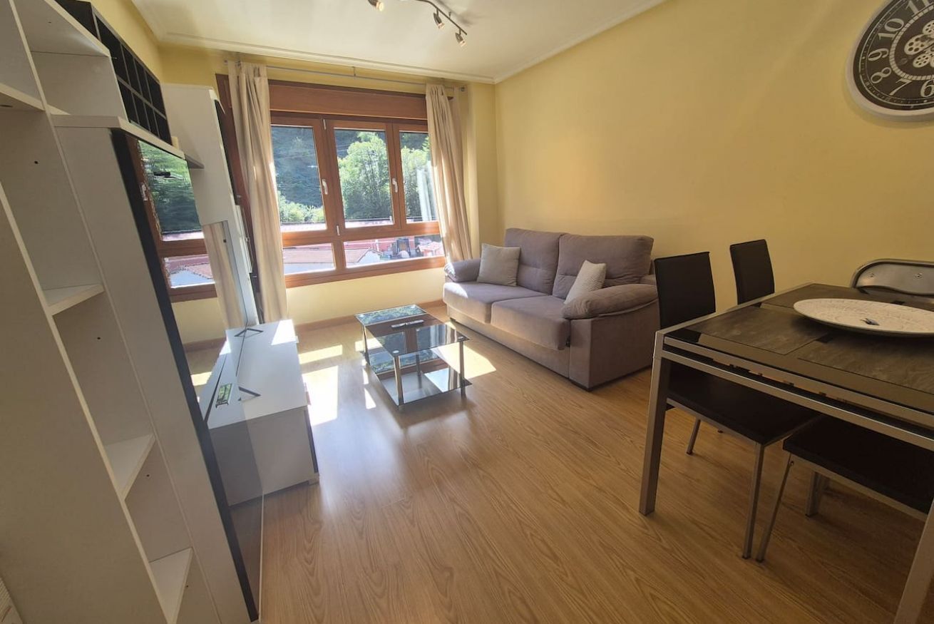 Uma sala de estar com sofá, mesa de jantar e televisão.