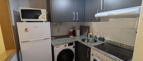 Cocina compacta equipada con microondas, refrigerador, lavadora, lavaplatos y estufa.