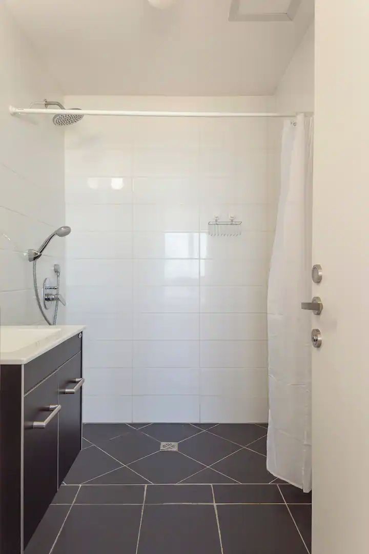 A small, modern bathroom with a shower, a toilet, and a sink.