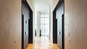 A modern hallway with wooden flooring and black walls, leading to a bright room with large windows. - Luxury Apt Tower Best Sea View Bat Yam (Bat Yam)