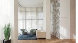 A modern living room with a sofa, a coffee table, and a large window with sheer curtains. - Luxury Apt Tower Best Sea View Bat Yam (Bat Yam)
