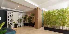 A modern lobby with a seating area, potted plants, and a bamboo wall. - XL Patong Hotel (Patong)
