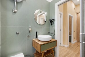 A bathroom with a round mirror, a sink, and a shower. - Merliani House Holiday Home (Napoli)